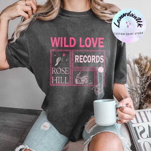 May include: A black t-shirt with a pink graphic design that says "WILD LOVE RECORDS" and "ROSE HILL".