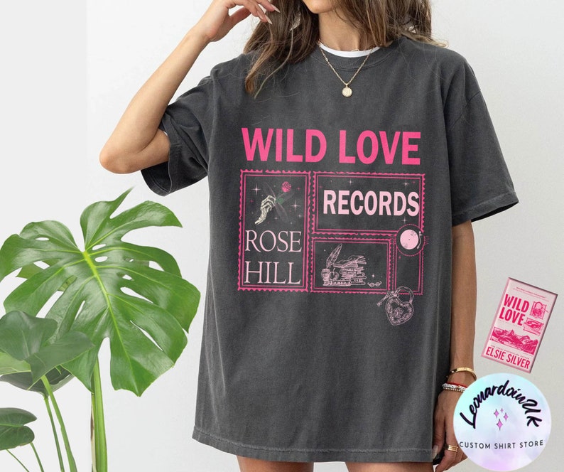 May include: A dark gray t-shirt with a pink graphic print that says "Wild Love Records Rose Hill". The graphic features a hand holding a rose, a vintage record player, and a heart.