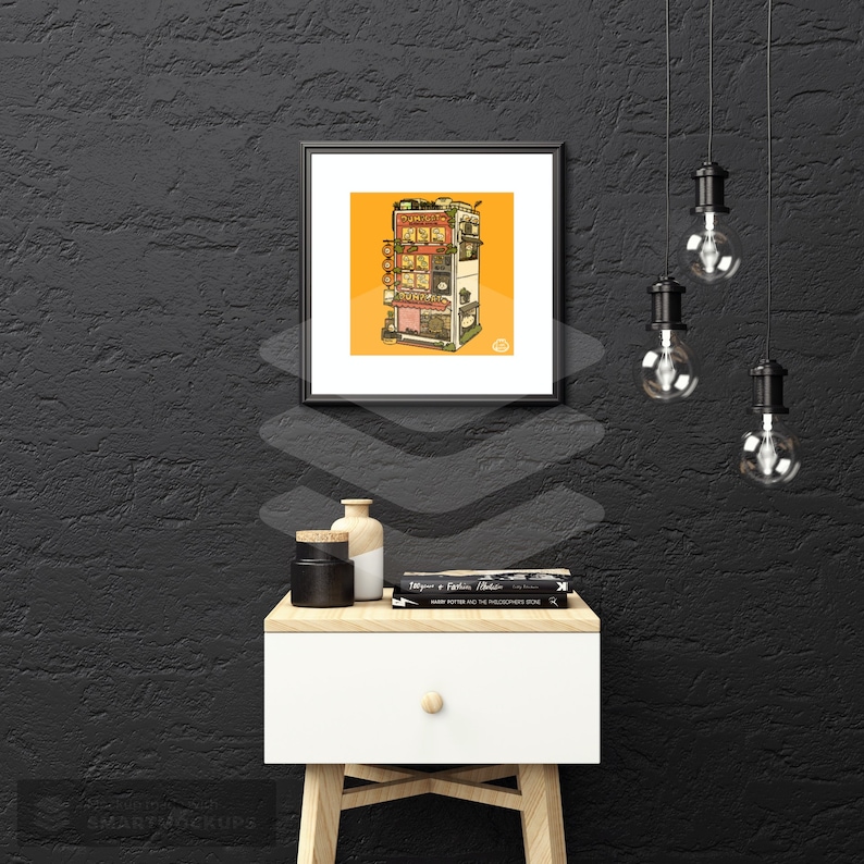 May include: A black framed print of a colorful illustration of a building with multiple storefronts. The building is set against a yellow background. The print is hanging on a black wall with a white nightstand and a lamp in the foreground.