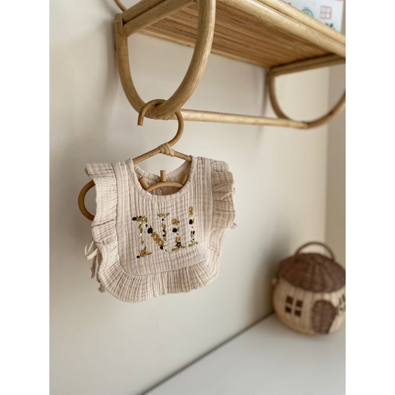 This adorable muslin bib is personalized with hand-embroidered details, making it the perfect accessory for your little one's mealtime adventures.