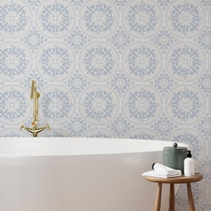 May include: A bathroom scene featuring a white bathtub, a small wooden stool, and a wall covered in patterned tiles. The tiles have a repeating circular design in light blue and white. A gold faucet is visible.