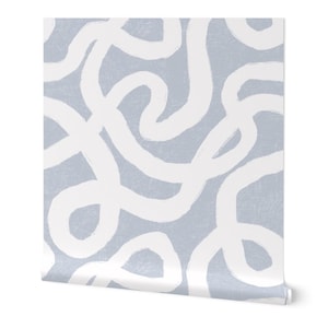 May include: A roll of wallpaper featuring a repeating pattern of thick, white, brushstroke-style lines on a light blue background. The lines are abstract and create a flowing, organic design. The wallpaper is rolled up.