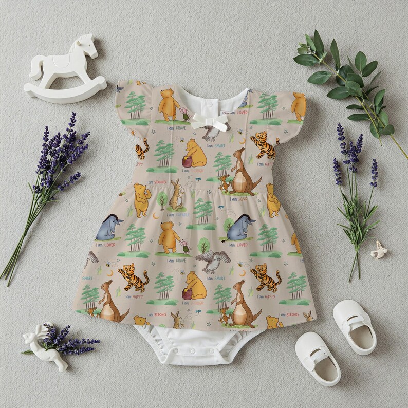 May include: A beige baby onesie with a Winnie the Pooh and friends print. The onesie features a variety of characters including Winnie the Pooh, Tigger, Piglet, Eeyore, and Roo. The onesie has a white trim around the neckline and sleeves.