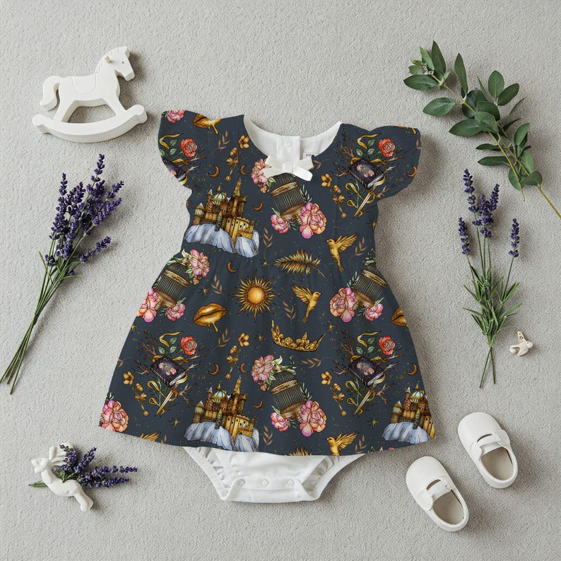 May include: A dark blue baby dress with a whimsical pattern of castles, flowers, birds, and suns. The dress has flutter sleeves and a white bow at the neckline. White baby shoes and a rocking horse are also in the image.