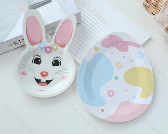 May include: Two paper plates with Easter themes. One plate features a bunny rabbit with pink ears and a white face. The other plate has a pastel blue, pink, and yellow abstract design with white hearts and flowers.