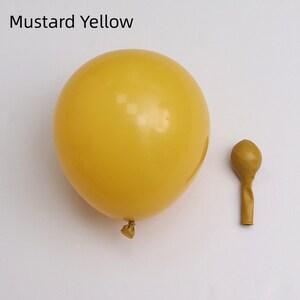 May include: Two mustard yellow balloons, one inflated and one deflated. The inflated balloon is larger than the deflated balloon.