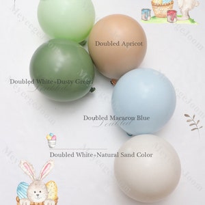 May include: Five pastel colored balloons with the text "Doubled Macaron Mint", "Doubled Apricot", "Doubled White+Dusty Green", "Doubled Macaron Blue", and "Doubled White+Natural Sand Color" printed on each balloon. A watercolor illustration of a bunny holding a paintbrush and a basket of Easter eggs is in the upper right corner of the image. The text "Easter" is printed in the lower right corner of the image.