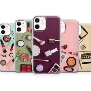 Może przedstawiać: Pięć przezroczystych etui na telefon z różnymi wzorami makijażu. Każde etui zawiera różne produkty do makijażu, w tym palety cieni do powiek, szminkę, lakier do paznokci i pędzle. Etui są przezroczyste i pokazują telefon przez wzór.