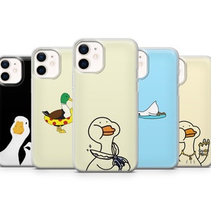 May include: Five different phone cases with various designs featuring cartoon ducks. The cases are clear and show the phone's camera lens. The designs include a duck wearing a life preserver, a duck with scissors, a duck with a necklace, a duck with a crown, and a duck with a crown.