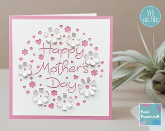 May include: A white card with a pink border features a cut-out design of flowers and hearts surrounding the text "Happy Mother's Day".
