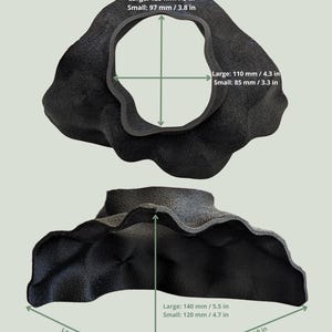 May include: Two black, organically shaped sculptures are shown, one above the other. The top sculpture has a large central opening. Measurements are provided in inches and millimeters: 5 in, 4.3 in, 5.5 in, and 9 in. The bottom sculpture has a similar shape, with measurements of 6.9 in, 4.7 in, and 9 in.