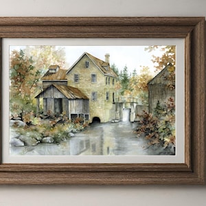 May include: Watercolour painting of a historic grist mill in a wooden frame. The mill is constructed from stone and has a wooden roof. The surrounding landscape includes trees with autumn foliage, a river, and a small bridge. The artwork is framed in a brown wooden frame.