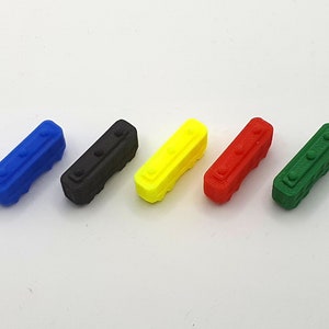 Può includere: Cinque piccoli blocchi di plastica di diversi colori: blu, nero, giallo, rosso e verde. Ogni blocco ha un design in rilievo sulla parte superiore.