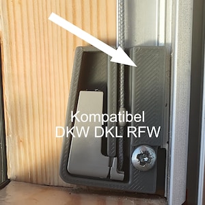 Pode incluir: Close-up de um componente de janela cinza com o texto "Kompatibel DKW DKL RFW". O componente está fixado a uma moldura de madeira e a um trilho de metal. Um cabo de metal passa pelo componente.