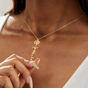 May include: A gold-colored necklace featuring a sunflower design and the name "Halle" in a delicate script. The pendant hangs from a fine chain, creating an elegant and personalized accessory. The necklace is worn around the neck.