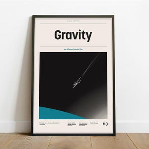 May include: A black and white minimalist movie poster for the film "Gravity", an Alfonso Cuarón film. The poster features a black background with a white astronaut floating in space, with a blue planet in the distance. The title "Gravity" is in bold white text at the top of the poster.
