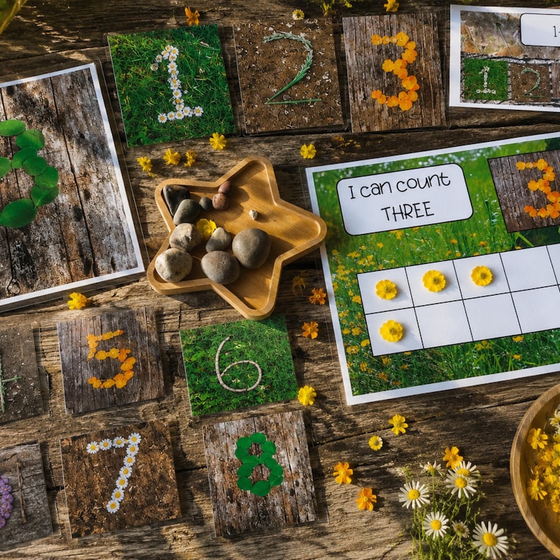 Op de afbeelding: Houten educatieve telset met de cijfers 1-8, elk versierd met bloemen of bladeren. Een stervormige houten schaal bevat kleine stenen. Een kaart leest "I can count THREE". Madeliefjes en gele bloemen zijn verspreid.