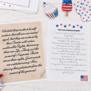 K&ouml;nnte beinhalten: Zwei rechteckige Karten mit patriotischen Motiven. Eine Karte zeigt den Text der Unabh&auml;ngigkeitserkl&auml;rung auf gealtertem Pergamentpapier. Die andere Karte enth&auml;lt den Liedtext von The Star-Spangled Banner mit blauen und roten Sternen.