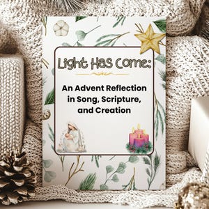 May include: A decorative card with the text "Light Has Come: An Advent Reflection in Song, Scripture, and Creation." The card features illustrations of a star, candles, and a religious figure, with a background of green leaves and white flowers.