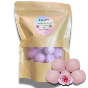 Op de afbeelding: Een zakje met 20 rozengeurende badbruisballen, met het label "Premium Bath Bombs" van "BWOW Cosmetics". De bruine zak heeft een doorzichtig venster met de roze badbruisballen. Verschillende badbruisballen liggen buiten de zak, samen met een roze roos.