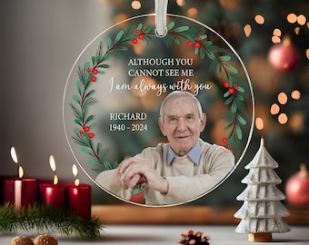 May include: A clear round Christmas ornament with a green wreath and red berries. The ornament features a photo of a man and the text "Although you cannot see me I am always with you Richard 1940-2024".