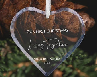 May include: Clear heart-shaped Christmas ornament with the text "Our First Christmas Living Together Victor + Nadia 2024"