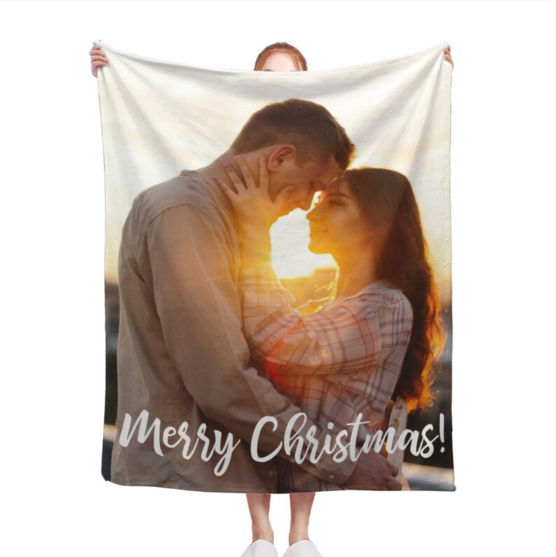 May include: A fleece blanket featuring a photograph of a couple embracing at sunset. The text "Merry Christmas!" is printed at the bottom of the blanket.
