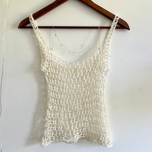 Puede incluir: Un top blanco de crochet con un delicado collar de cadena en forma de estrella.