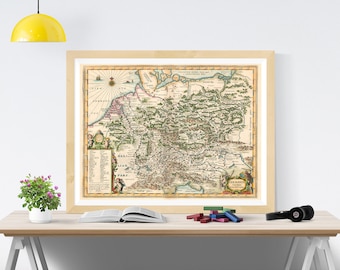 May include: A framed antique-style map of Germania featuring detailed cartography, a compass rose, and decorative cartouches with Latin text. The map displays historical geographical regions with green-shaded forests and tan landmasses.