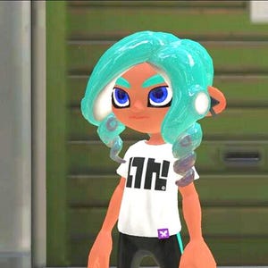 May include: A digital character with bright turquoise, tentacle-like hair, deep blue eyes, and tan skin. The character wears a white short-sleeved t-shirt featuring a bold black graphic design on the front and a small purple tag at the hem.