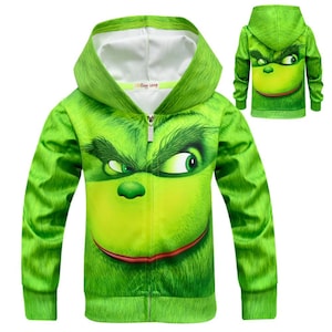 Pode incluir: Camisola de moletom verde com capuz, fecho de correr e estampa de rosto do Grinch. O Grinch está sorrindo com os olhos bem abertos.