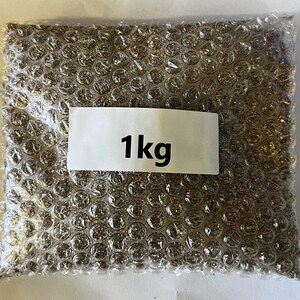 以下が含まれることがあります： 茶色の袋に「1kg」と書かれた白いラベルが付いており、茶色の物質で満たされています。袋は気泡緩衝材でできています。