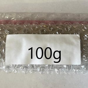 May include: A white bubble wrap package with a label that says "100g".