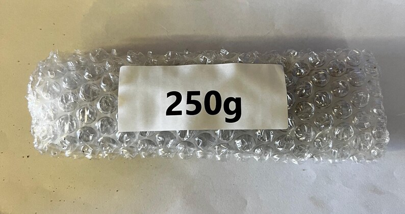 以下が含まれることがあります： 白いラベルに黒い文字で「250g」と印刷された、プチプチで包まれたパッケージです。