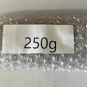 May include: A white bubble wrap package with a white label that says "250g".