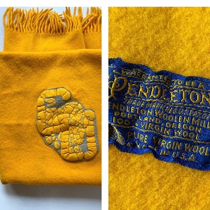 May include: A yellow Pendleton wool scarf with a fringe border and a blue label that reads "Pendleton Woolen Mills, Portland, Oregon, 100% Virgin Wool, Pure Virgin Wool".