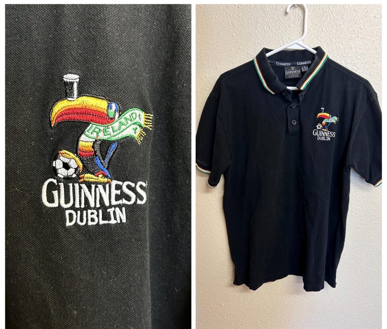 May include: Black polo shirt with a white, green, and red striped collar and sleeve cuffs. The shirt features an embroidered Guinness Dublin logo with a toucan, soccer ball, and the word "Ireland".