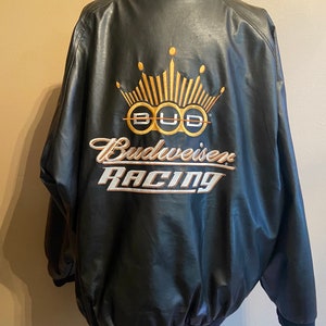 May include: Black leather jacket with a gold embroidered Budweiser Racing logo. The logo features a crown and the words "Budweiser Racing".