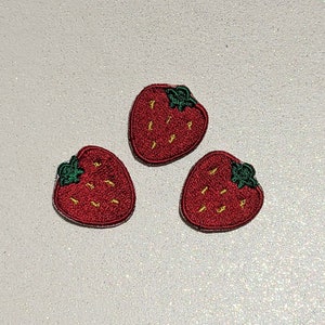 以下が含まれることがあります： 緑の葉と黄色の種が付いた赤い刺繍のイチゴのパッチが3つあります