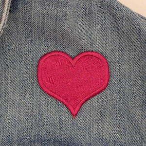 May include: A denim jacket with a pink heart patch sewn on the front.
