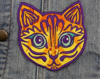 May include: A colorful embroidered cat patch with yellow, orange, purple, and green details. The cat's eyes are large and green, and the patch is sewn onto a denim jacket.