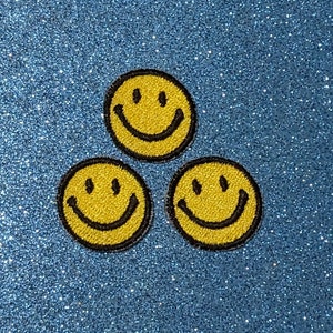 May include: Three yellow smiley face patches on a blue sparkly background.