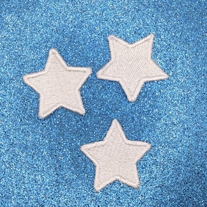以下が含まれることがあります： 青いキラキラした背景に、白いフェルトの星が3つある。