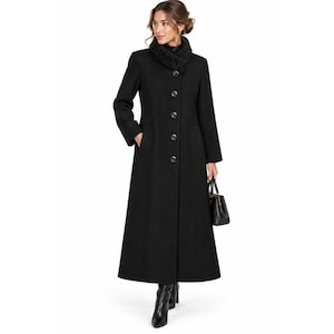 May include: A long, black, floor-length coat featuring a high collar, long sleeves, and a front button closure. The coat is paired with a black handbag and black boots. The design includes a textured, dark, fuzzy scarf worn around the neck.