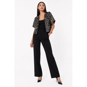 May include: A black sequined bolero jacket with short sleeves, paired with black trousers and heels. The jacket is adorned with gold and silver sequins. The outfit is a formal ensemble.