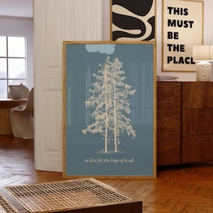 May include: A framed print with a blue background and a white outline of two pine trees. The text "to live for the hope of it all" is at the bottom of the print.