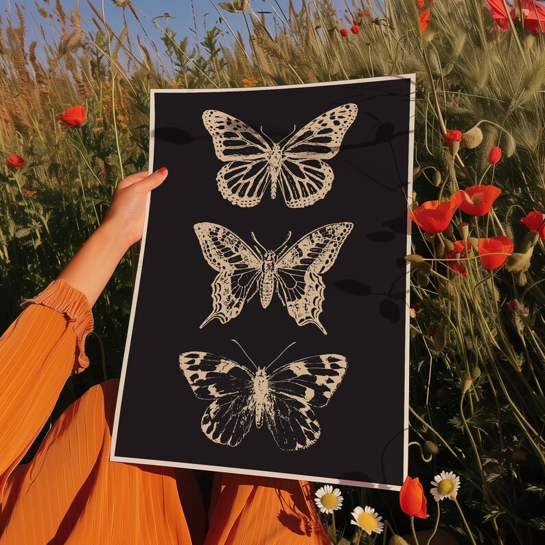 May include: A black poster with three white butterfly silhouettes. The butterflies are arranged vertically, with the largest butterfly at the top and the smallest butterfly at the bottom. The butterflies have intricate wing patterns.
