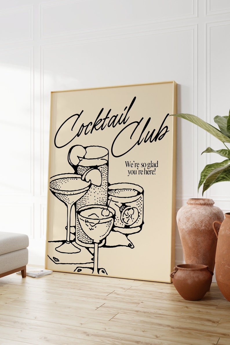 May include: A framed poster with a beige background features a black and white illustration of cocktail glasses and drinks. The text "Cocktail Club" is written in cursive, with the phrase "We're so glad you're here!" below the illustrations.