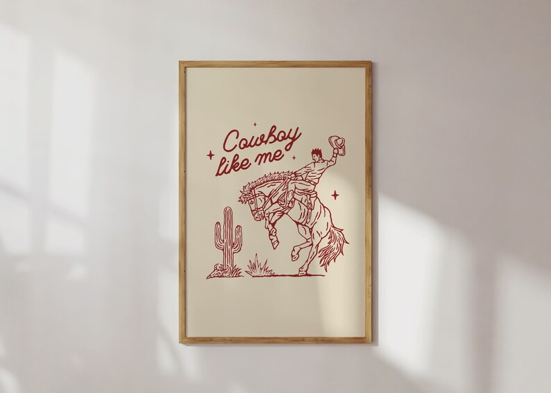 Może przedstawiać: Oprawiony wydruk z beżowym tłem przedstawia czerwony rysunek linii przedstawiający kowboja na koniu rodeo. Tekst "Cowboy like me" znajduje się nad ilustracją. Kaktus znajduje się po lewej stronie konia.