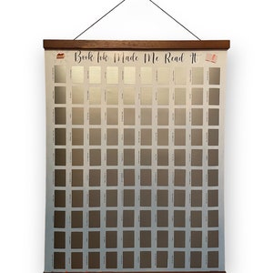 May include: A white poster with a wooden frame and a black string for hanging. The poster has a grid of 100 squares, each with a different shade of grey. The poster has the text "Book Tok Made Me Read It" at the top.
